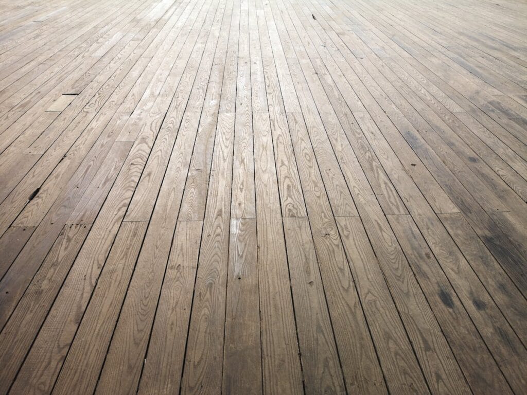 Aged hardwood floor planks showing natural texture - repair vs replacement decision in Spring TX